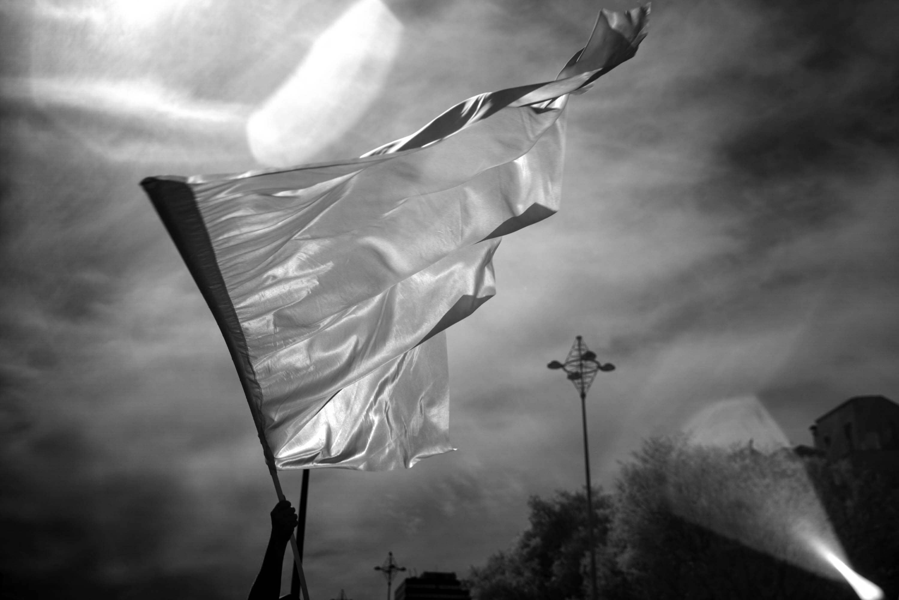 A flag is waved against a cloudy sky in Lisbon. The infrared camera cannot see the image printed on the flag, so it appears empty.