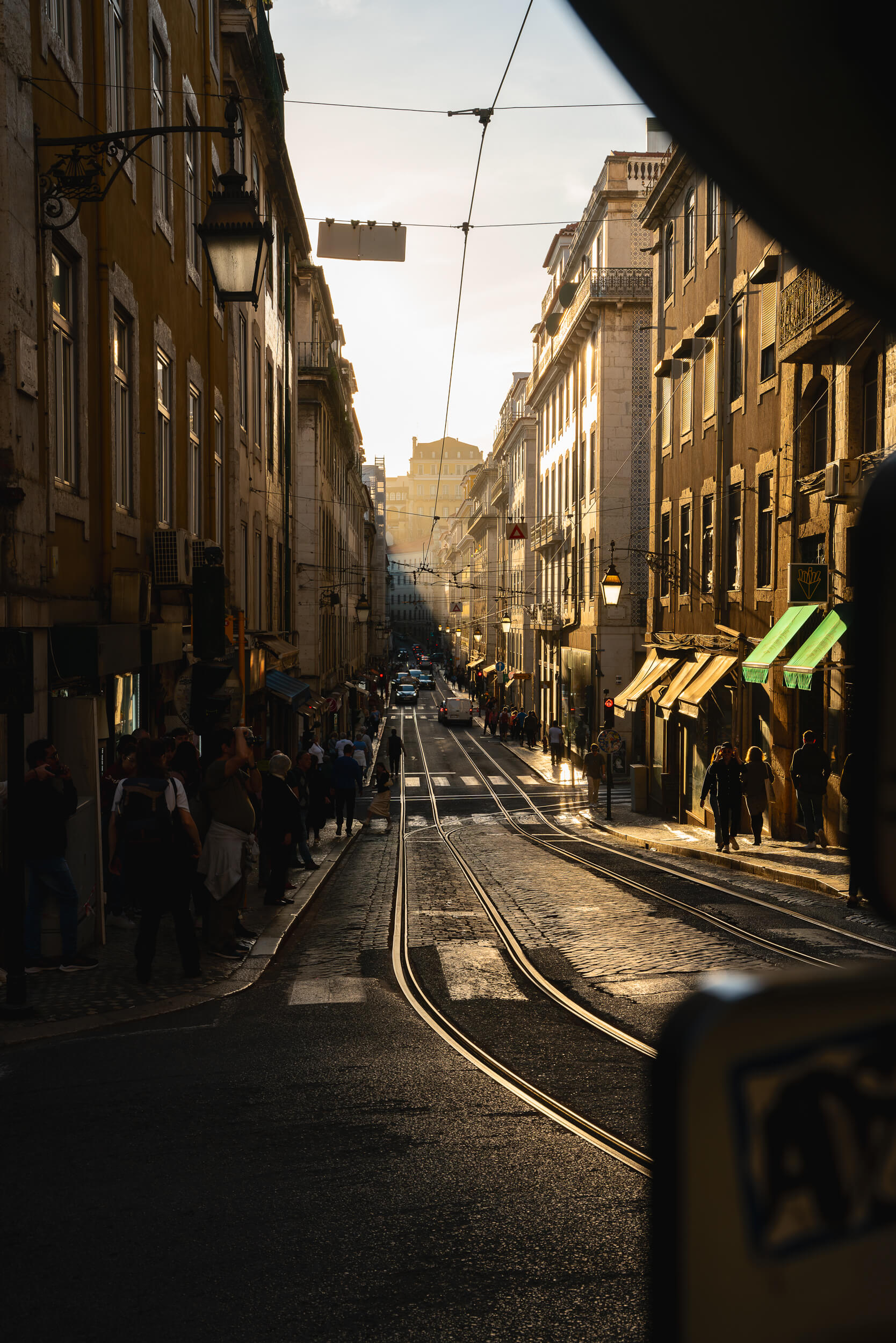 Lisbon's golden light pours over the city in front of Igreja de Santa Maria Madalena de Lisboa. The angle of the sun keeps one side of the street in darkness while illuminating the other.