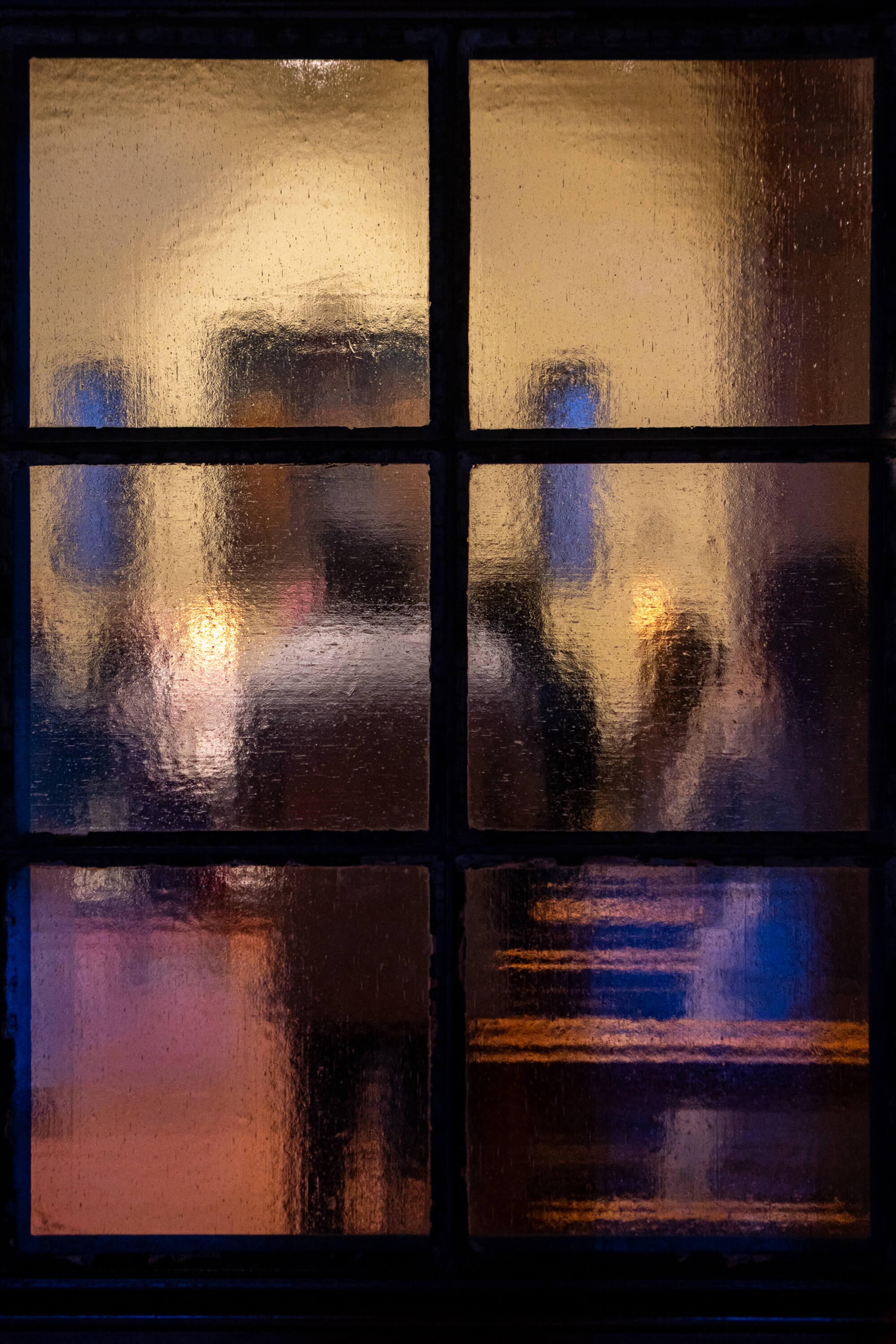 Churchgoers are obscured by old textured glass. Divided into six segments, the glass gives the people behind it an almost painterly look.