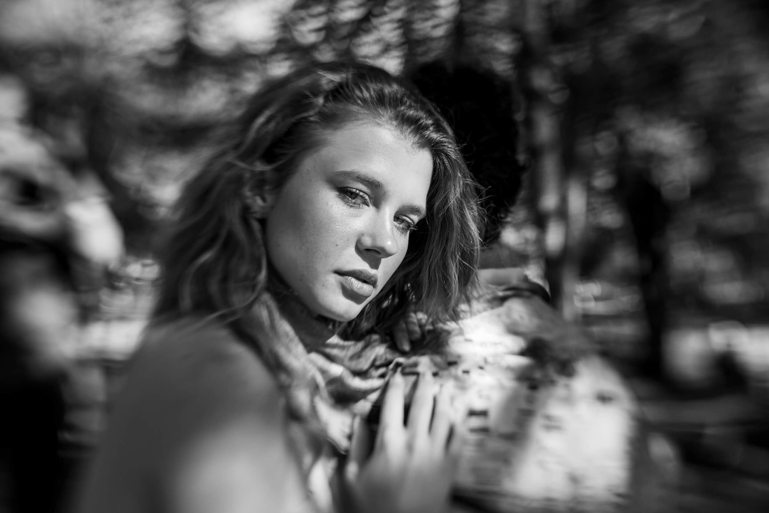A model rests her hand on another model's back. She stares sideways towards the camera with sultry eyes.